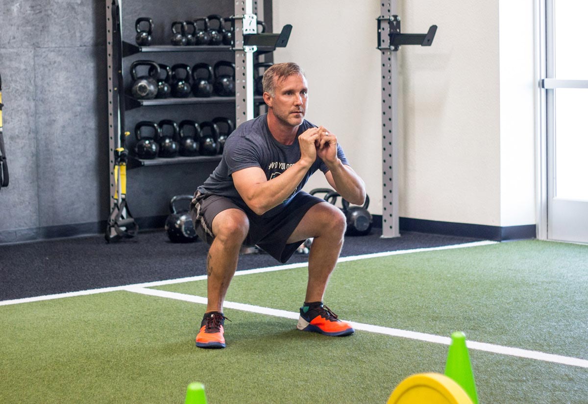 Male Trainer doing a bodyweight squat