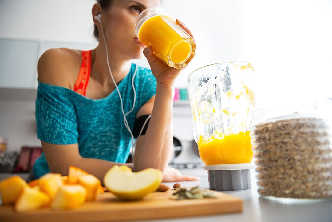 Woman drinking a glass of fresh squeezed orange juice after a workout