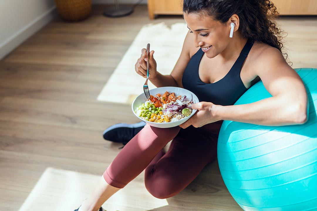 Woman eating a healthy grain bowl after an exercise class