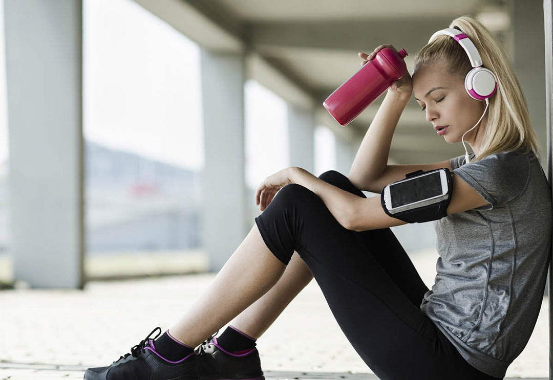 A woman in fitness gear looking defeated and tired