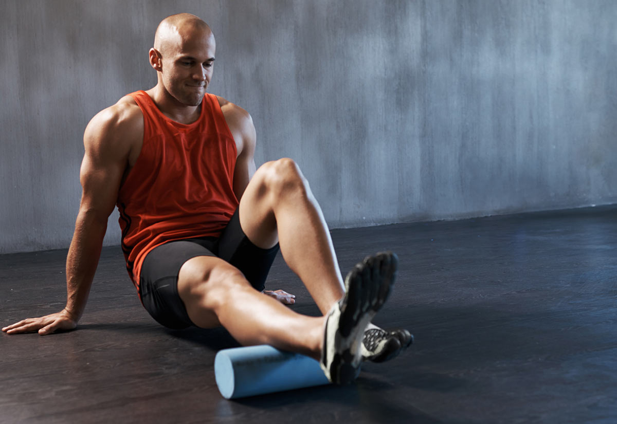A man using a foam roller to roll out his calf muscles