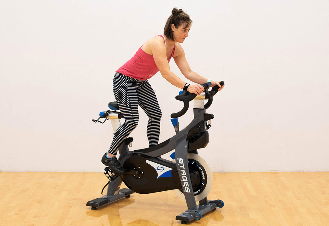 Woman out of the saddle on an indoor cycle bike