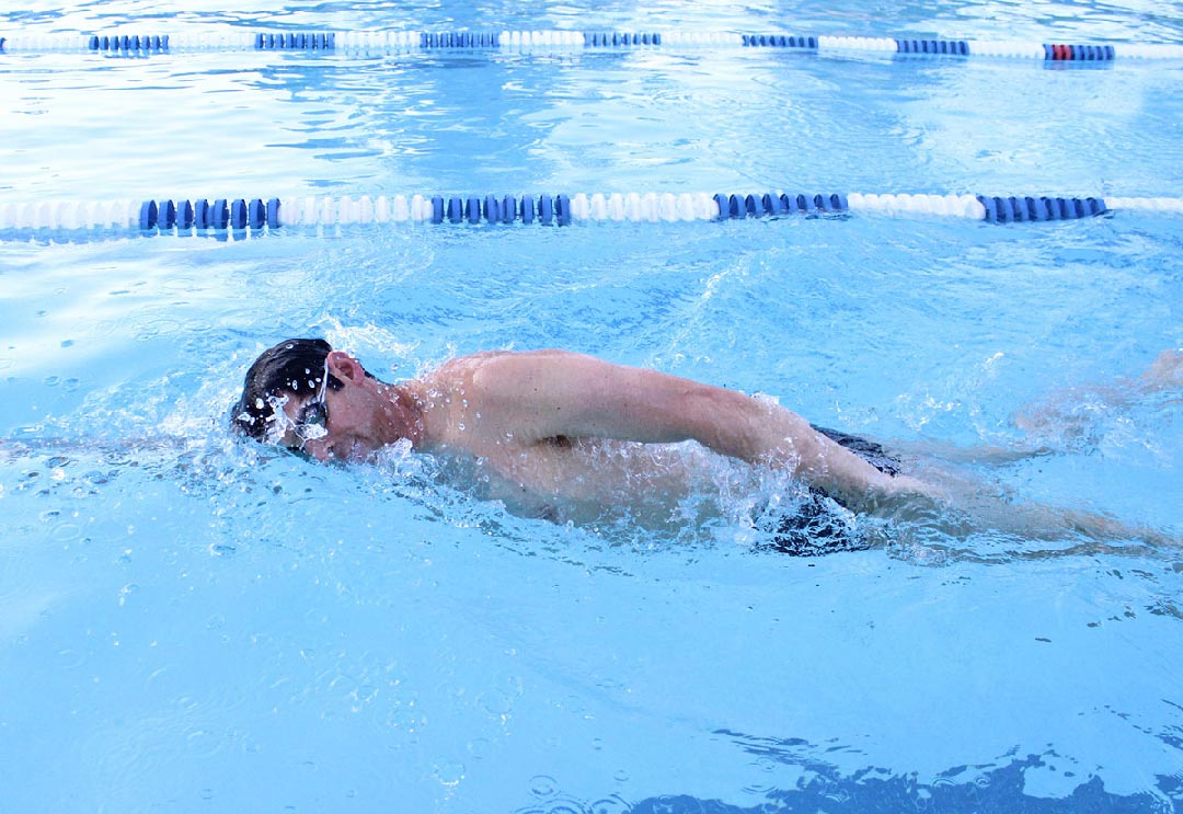 A man swimming laps in an outdoor lap pool