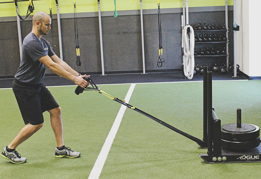 Male Personal Trainer pulling a sled on the Edge turf