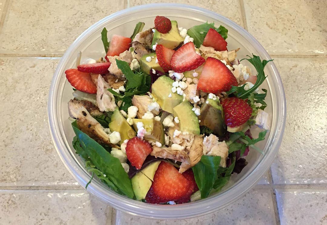 A nutritious salad with spinach, feta, avocado, and strawberries