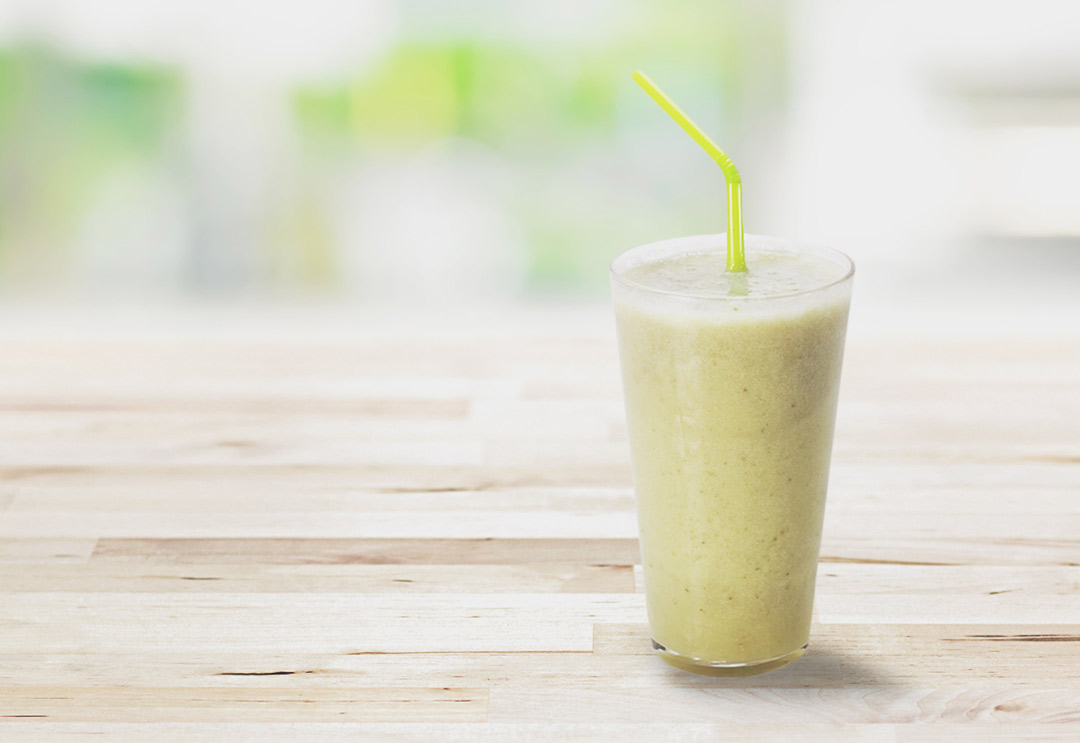 A nutrition lean green smoothie in a glass with a straw
