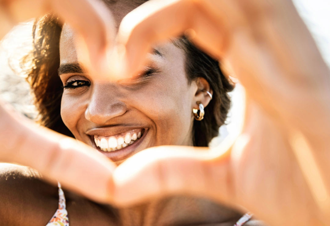 A woman smiling and making a heart with her hands